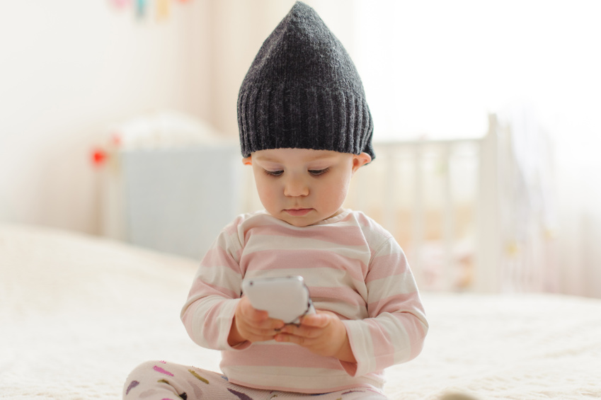 A Baby Playing with a Baby Monitor